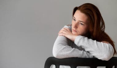 Medium shot of a woman sitting in a chair, looking visibly depressed