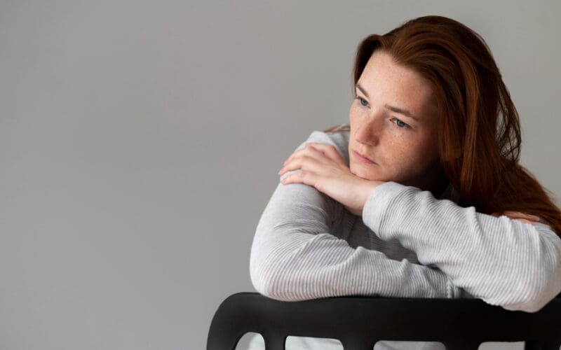 Medium shot of a woman sitting in a chair, looking visibly depressed