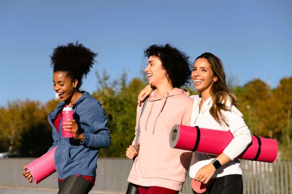 Medium shot of women with yoga mats getting ready for yoga exercises