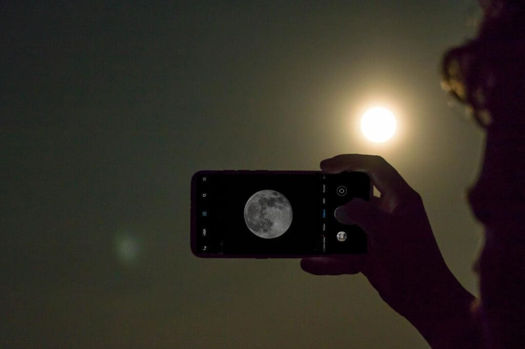 Person capturing images of the Moon with their smartphone