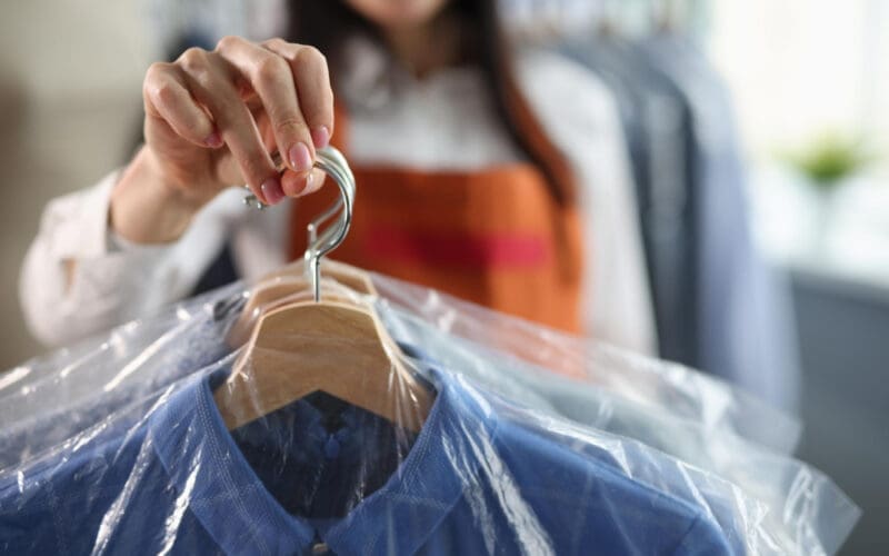 The female receptionist extends a freshly cleaned suit, freshly dry-cleaned and neatly pressed, towards the client