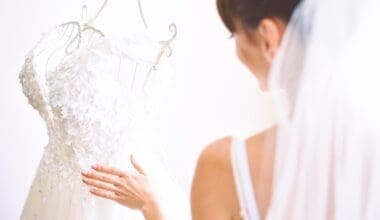 The elegant bride delicately drapes her white wedding gown in her room