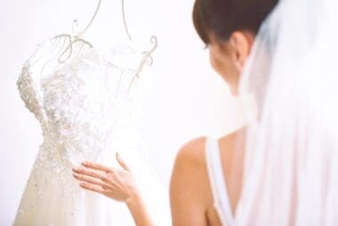 The elegant bride delicately drapes her white wedding gown in her room