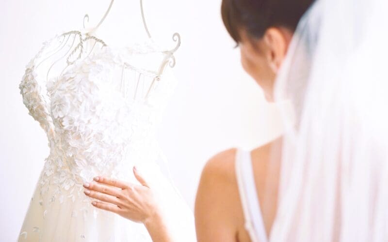 The elegant bride delicately drapes her white wedding gown in her room