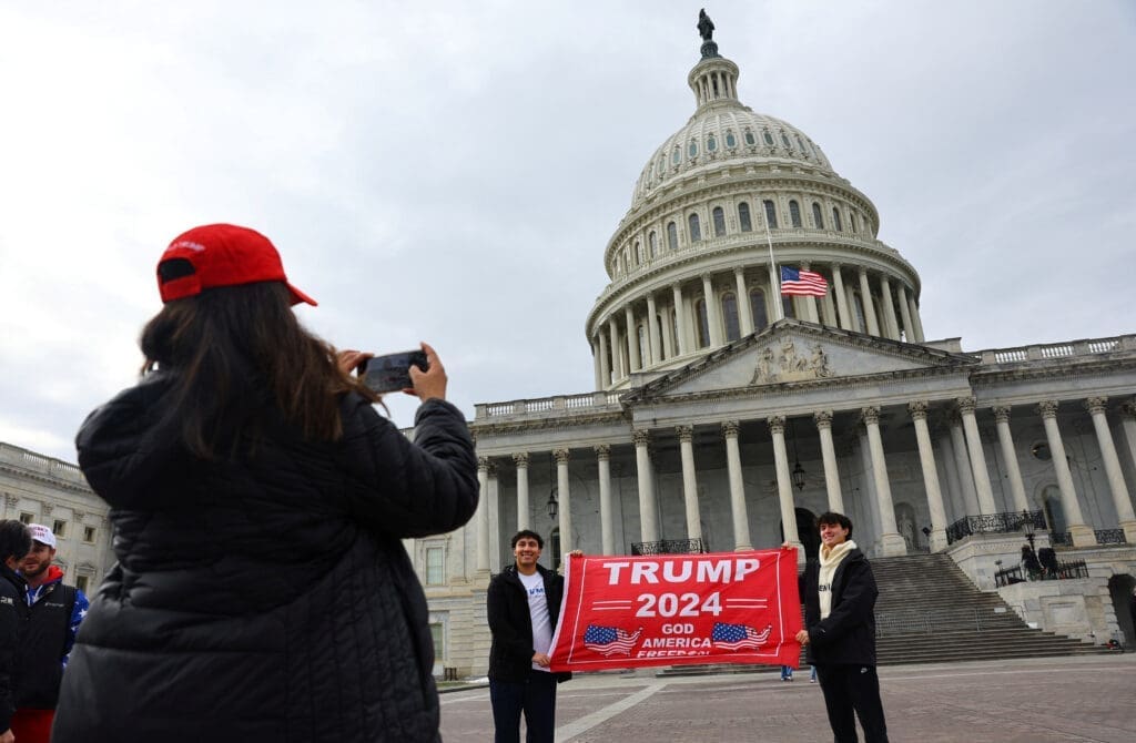 A woman uses a mobile phone as people hold a placard in favour of U.S. President-elect Donald Trump in Washington