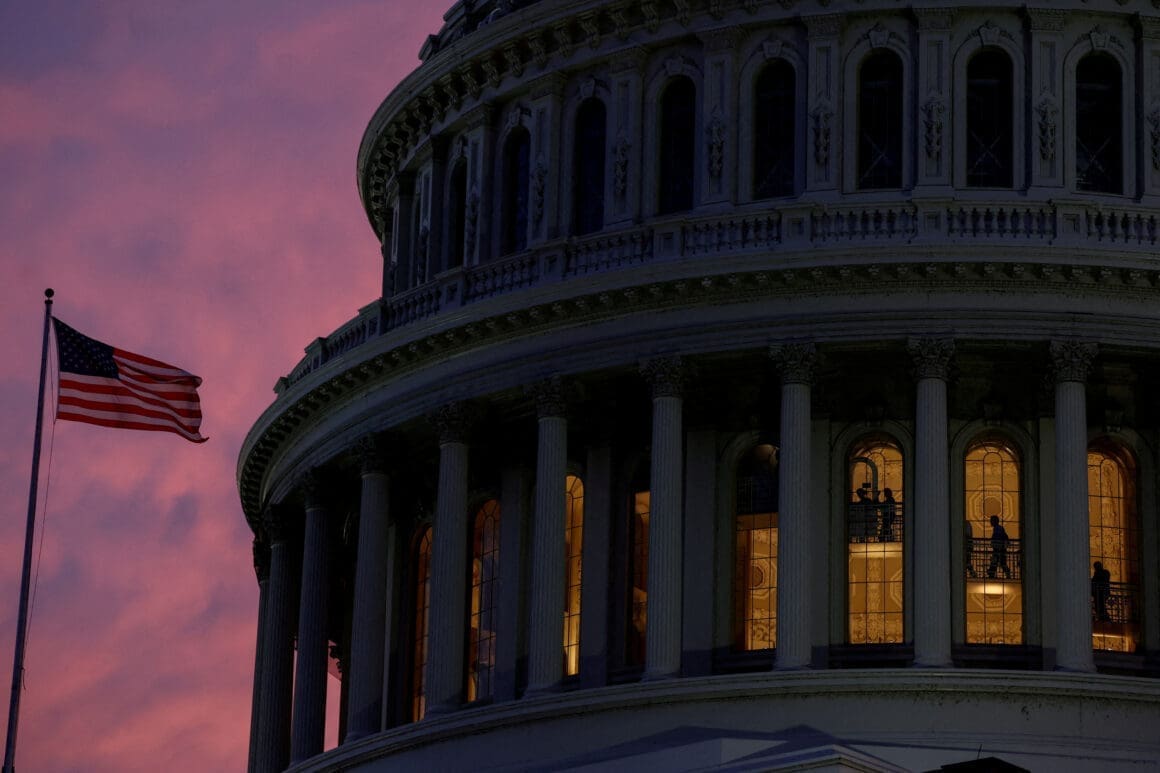 People walk inside the upper floors of the rotunda of the U.S. Capitol building at sunset in Washington