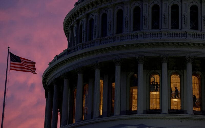 People walk inside the upper floors of the rotunda of the U.S. Capitol building at sunset in Washington