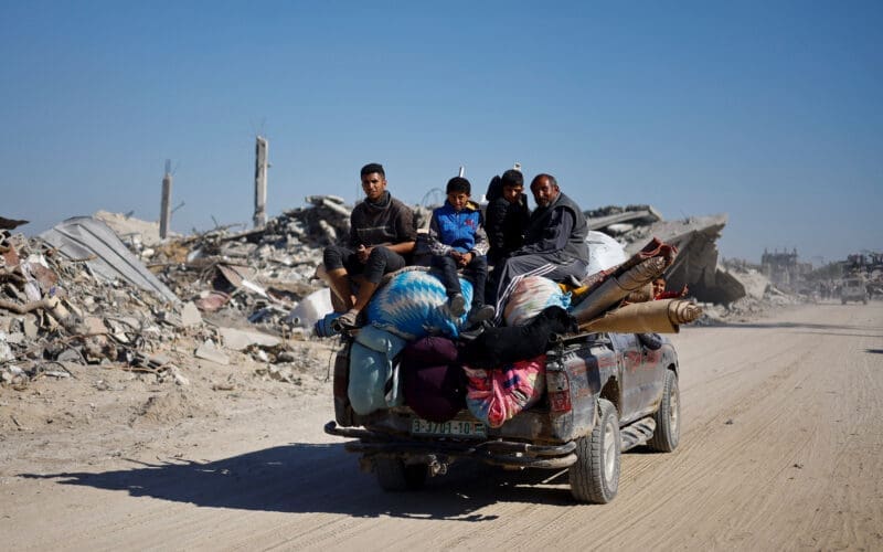 Palestinians ride a vehicle past the rubble of houses and buildings destroyed during the war, in Rafah