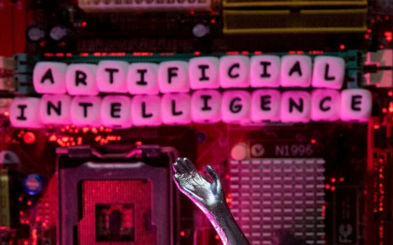 Illustration shows AI (Artificial Intelligence) letters and robot hand