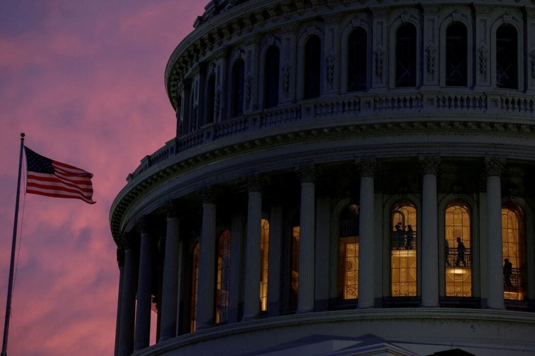 People walk inside the upper floors of the rotunda of the U.S. Capitol building at sunset in Washington