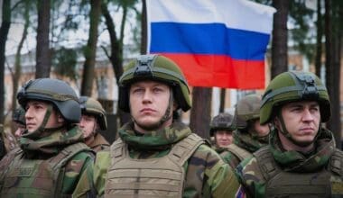 Troops stand in front of the Russian flag