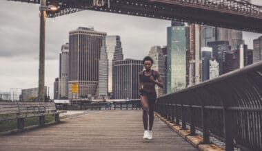 A full-length shot of a woman sprinting swiftly against a backdrop of a city skyline