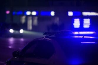 A blue police car light illuminates the night in the city, captured with selective focus