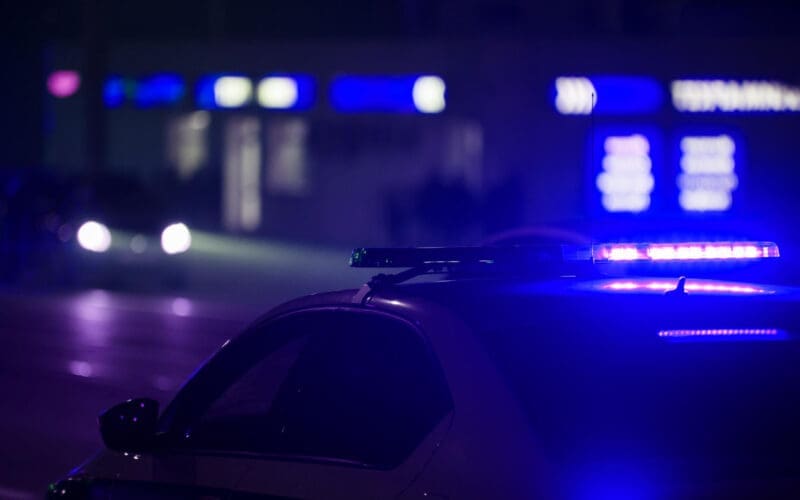 A blue police car light illuminates the night in the city, captured with selective focus