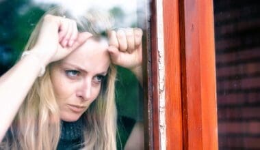 A frustrated woman stands by her window, irritated by the noise from her neighbor