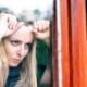 A frustrated woman stands by her window, irritated by the noise from her neighbor