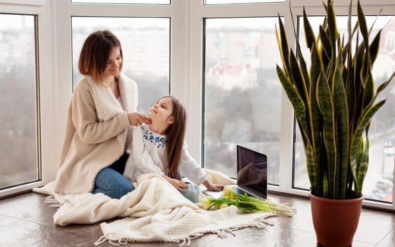 A mother and daughter sitting together on the floor at home