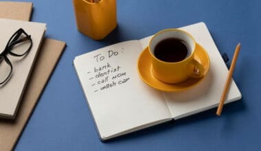 A notebook with a to-do list sits on a desk next to a cup of coffee