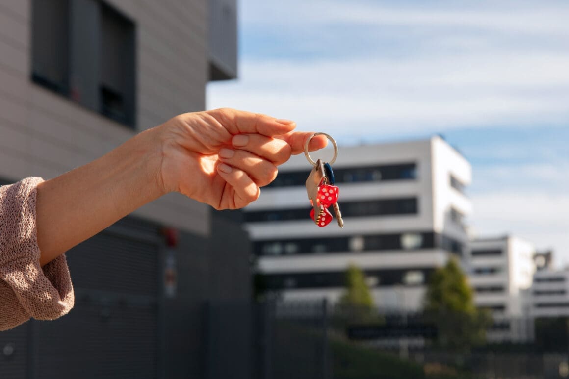 A person holding keys outside to signify the sale of a house