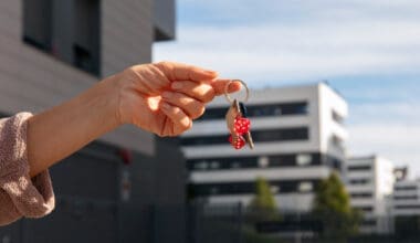 A person holding keys outside to signify the sale of a house