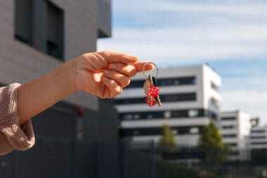 A person holding keys outside to signify the sale of a house