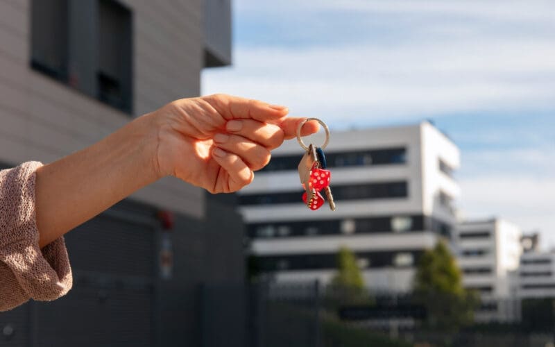 A person holding keys outside to signify the sale of a house