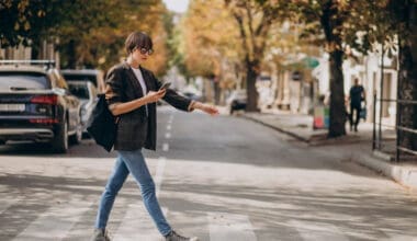 A young woman confidently crosses the road, embodying a sense of purpose and independence, her style reflecting modern trends as she navigates the bustling urban environment.