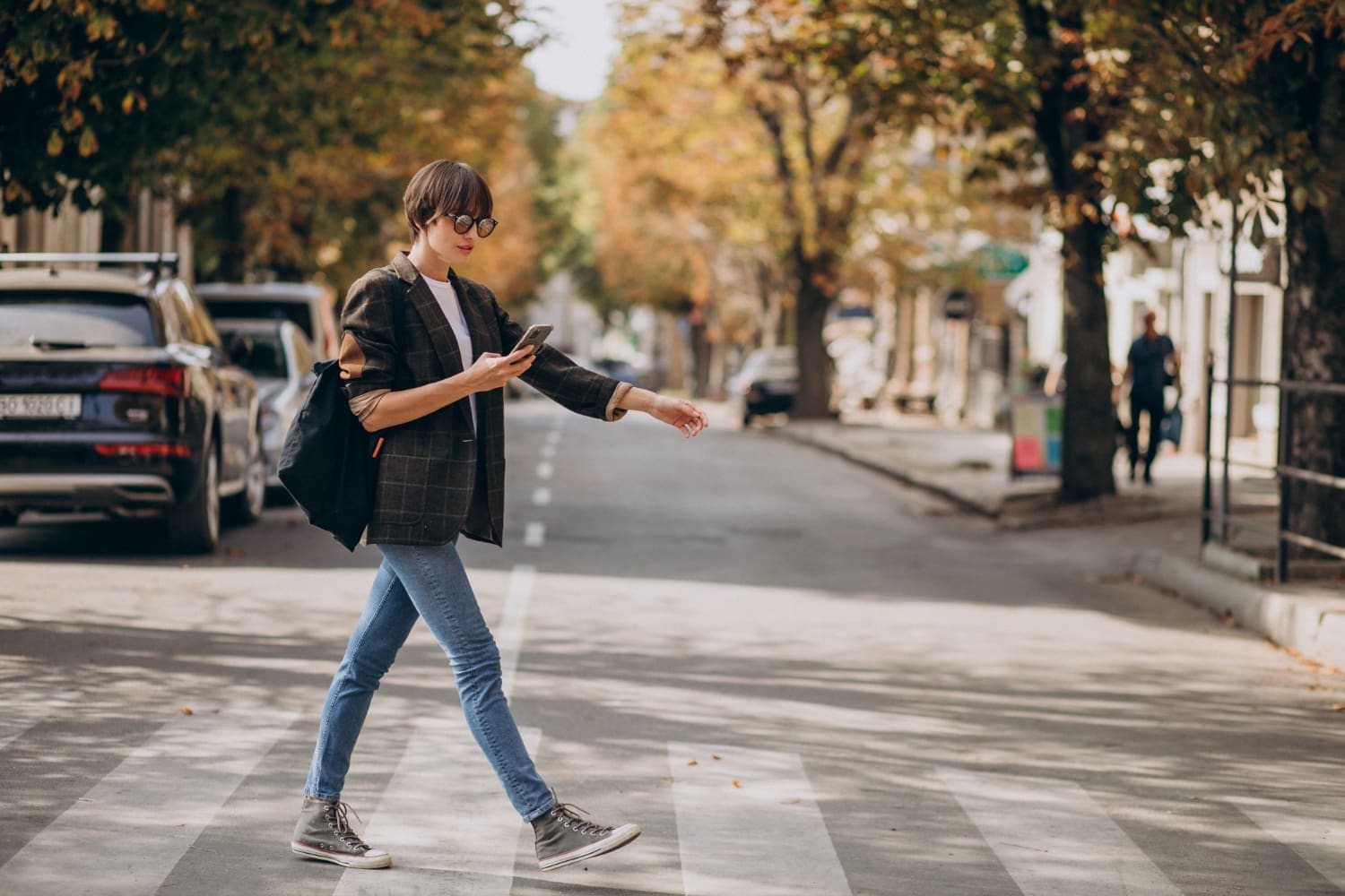 A young woman confidently crosses the road, embodying a sense of purpose and independence, her style reflecting modern trends as she navigates the bustling urban environment.