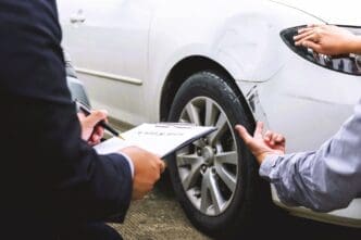 An insurance agent and a car owner assess minor damage to the vehicle's body