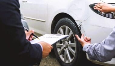 An insurance agent and a car owner assess minor damage to the vehicle's body