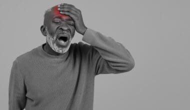 Black and white portrait of an elderly Black man featuring a bright red mark on his head, indicating an injury