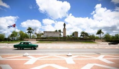 Classic car driving by a monument in Cuba