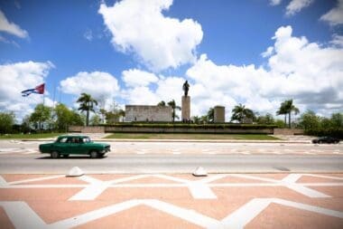Classic car driving by a monument in Cuba