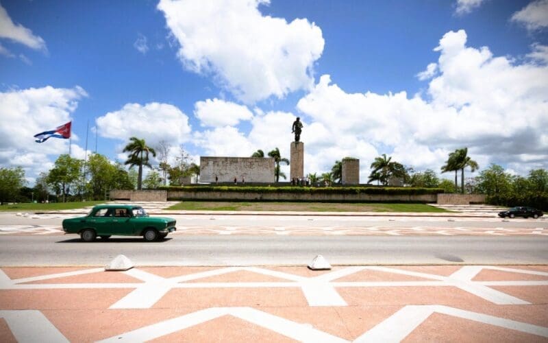 Classic car driving by a monument in Cuba