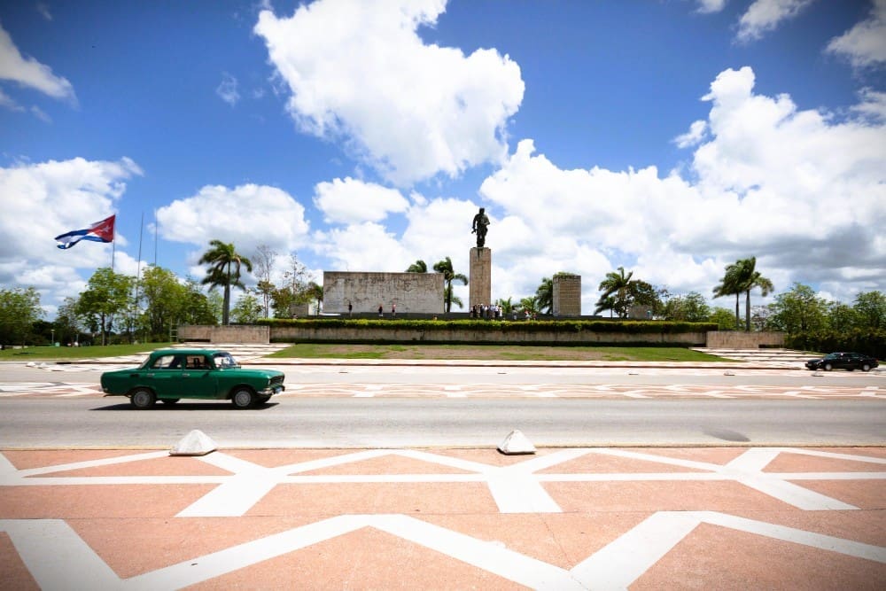 Classic car driving by a monument in Cuba
