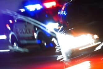 Close-up of a police car pursuit on a brightly lit street at night