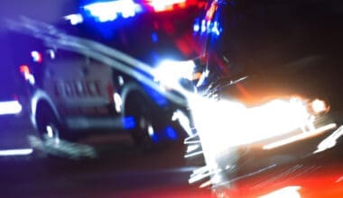 Close-up of a police car pursuit on a brightly lit street at night