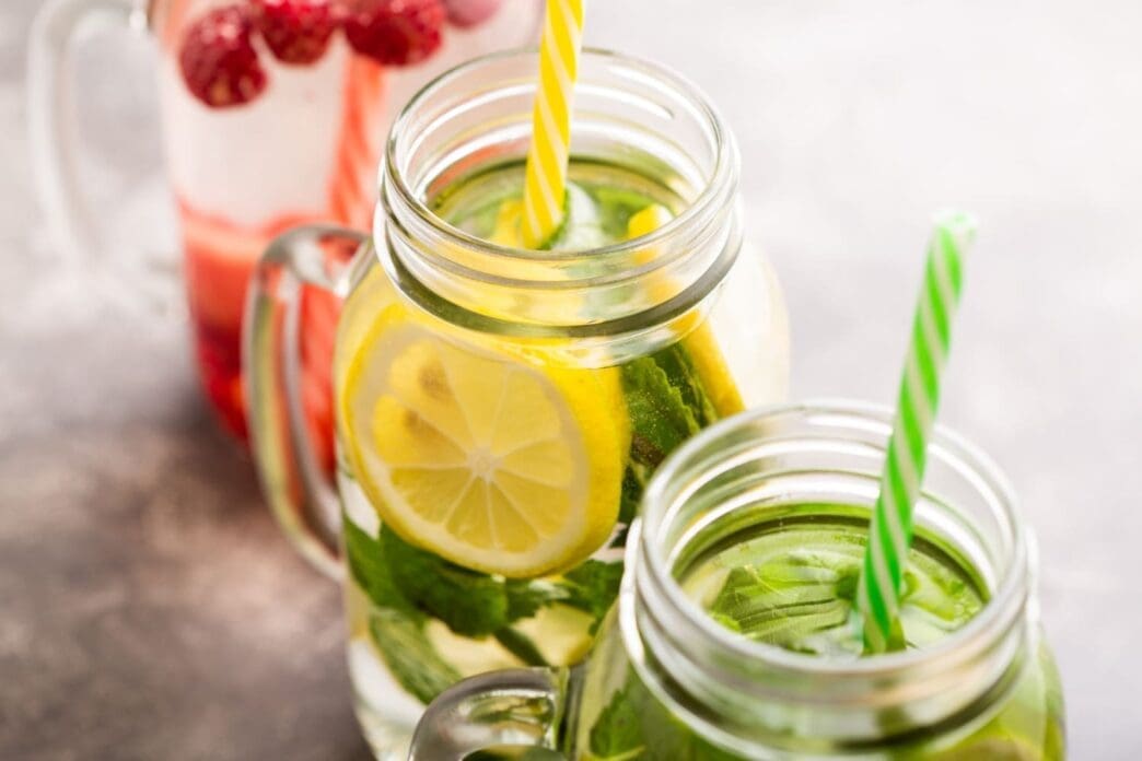 Detox water infused with raspberries, lemon, lime, and mint in three jars