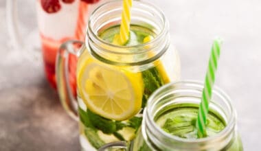 Detox water infused with raspberries, lemon, lime, and mint in three jars