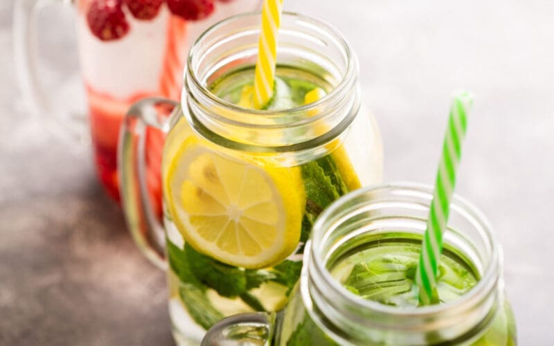 Detox water infused with raspberries, lemon, lime, and mint in three jars