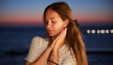 Feeling woman posing at sunset with an ocean view and gentle bokeh lights in the background