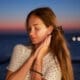 Feeling woman posing at sunset with an ocean view and gentle bokeh lights in the background