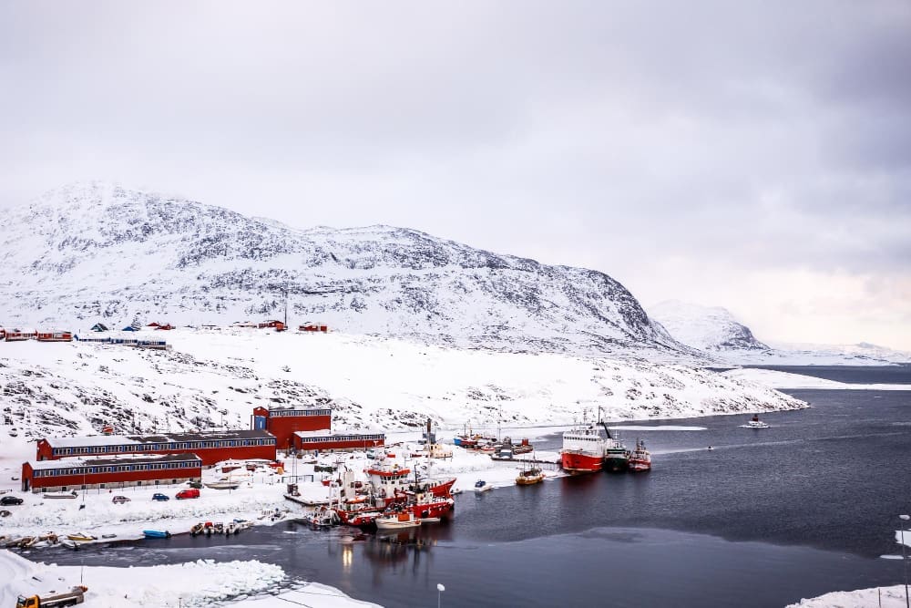 Fishing boats and harbor buildings with mountains in the background at the port of Nuuk, Greenland