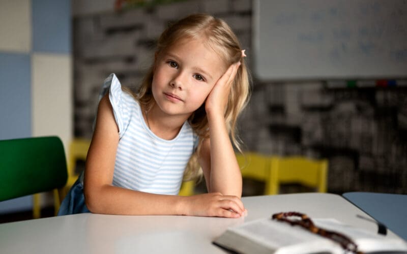 Front-facing view of a young girl seated at a table