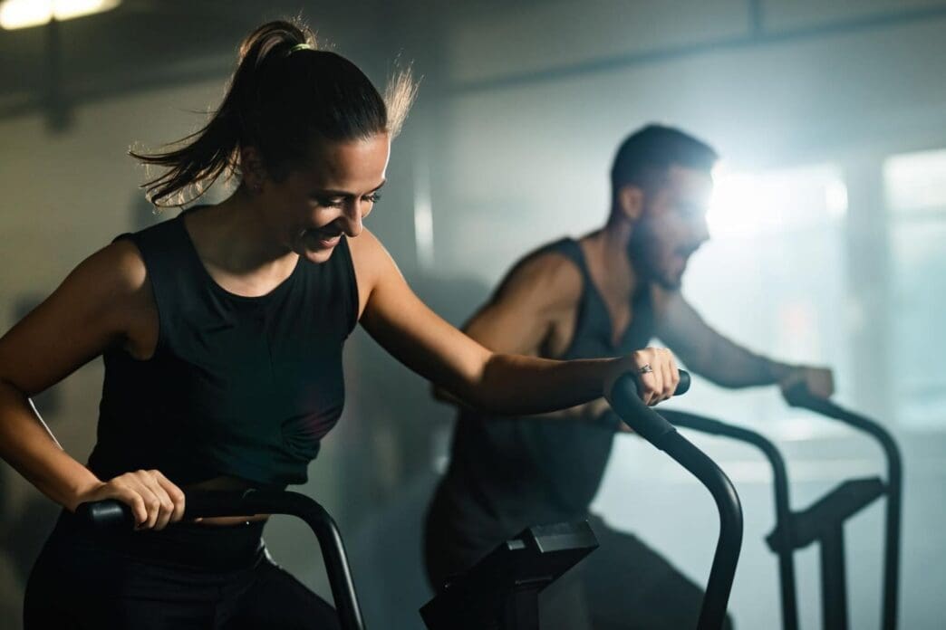 Happy couple cycling as part of their cross-training at a fitness center
