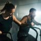 Happy couple cycling as part of their cross-training at a fitness center