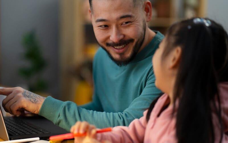 Profile view of a man assisting his daughter with her schoolwork