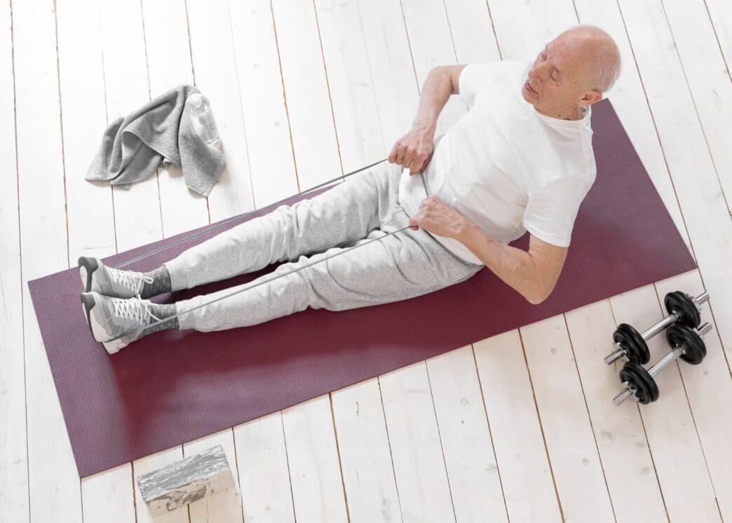 Wide shot of an elderly man exercising with a resistance band