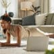 Woman Using Laptop to Do Plank Exercise at Home for Virtual Workout