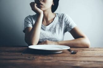Woman with an Empty Plate Struggling with Eating Disorders
